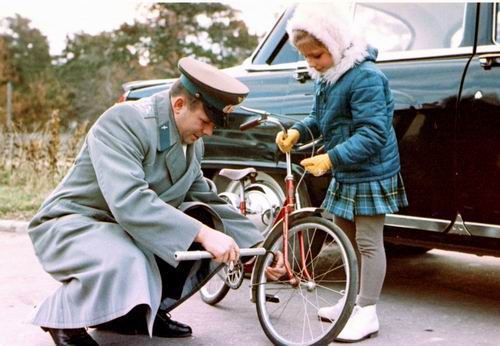 Гагарин накачивает колеса на велосипеде дочки