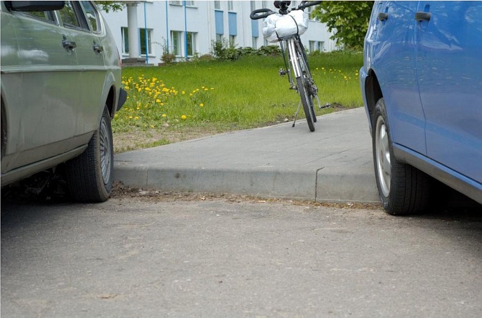 Велосипед между автомобилями на тротуаре